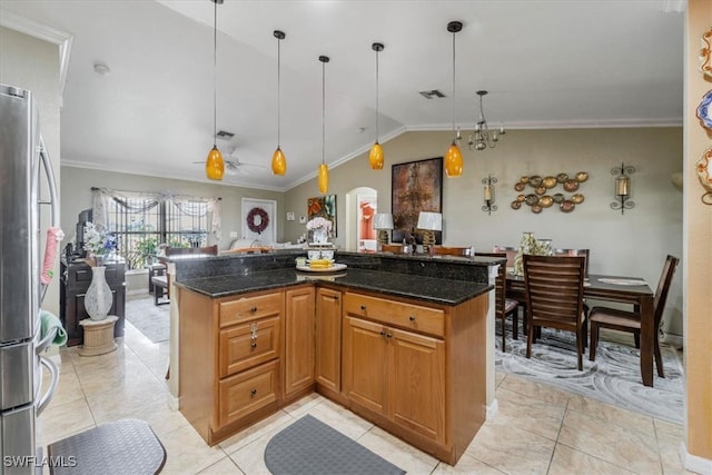 kitchen with decorative light fixtures, stainless steel fridge, dark stone countertops, and vaulted ceiling