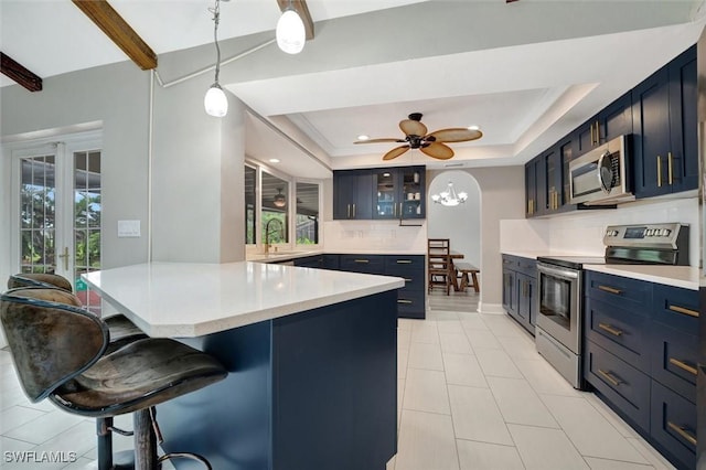 kitchen featuring hanging light fixtures, appliances with stainless steel finishes, backsplash, a tray ceiling, and a breakfast bar