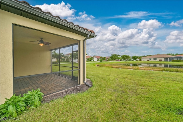 view of yard featuring a water view, ceiling fan, and a patio area