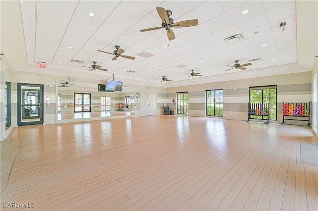 workout area featuring light wood-type flooring, ceiling fan, and a drop ceiling