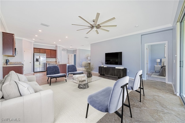 living room with crown molding, ceiling fan, and sink