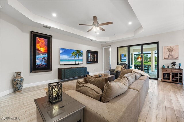 living room featuring a tray ceiling, ceiling fan, and french doors