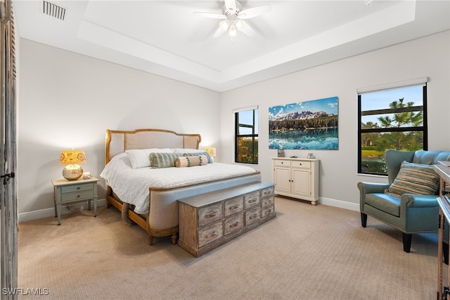 bedroom featuring multiple windows, a tray ceiling, and ceiling fan