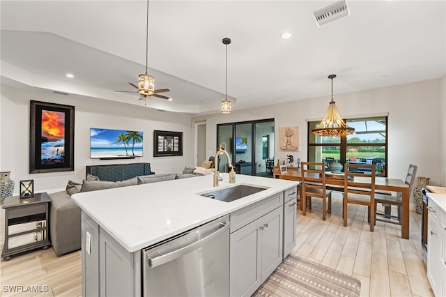 kitchen featuring a raised ceiling, ceiling fan, sink, a center island with sink, and dishwasher