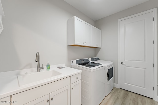 washroom with cabinets, independent washer and dryer, sink, and light hardwood / wood-style flooring