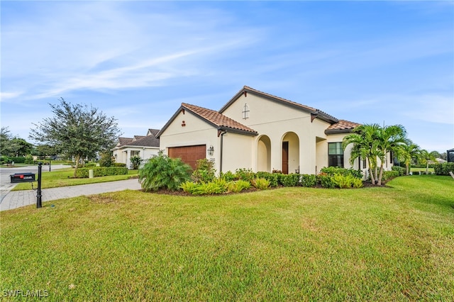 mediterranean / spanish-style house featuring a garage, stucco siding, driveway, and a front yard