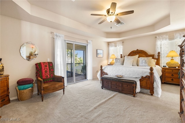 bedroom with ceiling fan, multiple windows, access to outside, and a tray ceiling