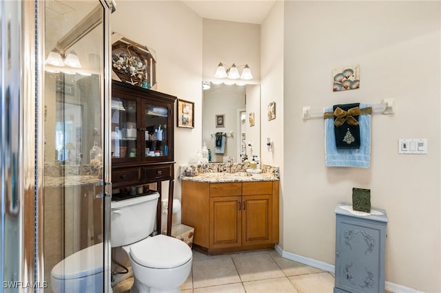 bathroom featuring tile patterned flooring, vanity, toilet, and walk in shower