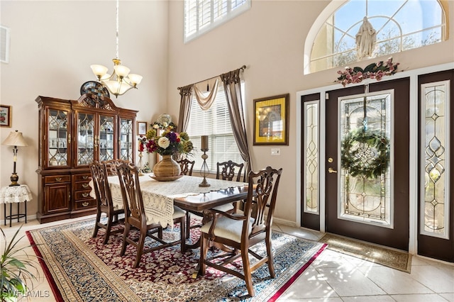 dining space featuring light tile patterned floors, a chandelier, and a high ceiling