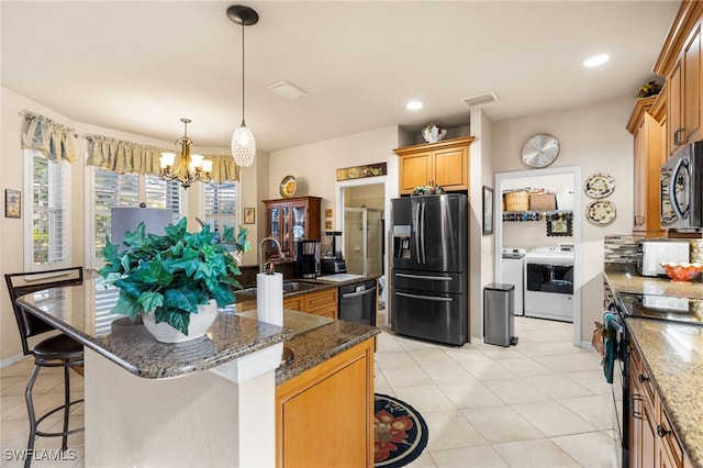 kitchen with sink, stainless steel appliances, washer and clothes dryer, and a kitchen island with sink