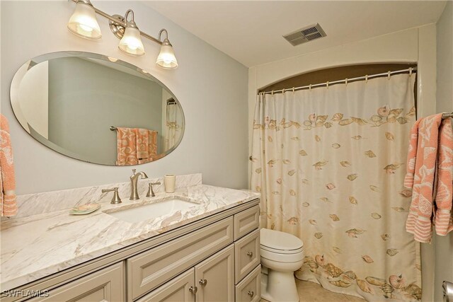 bathroom featuring tile patterned flooring, vanity, toilet, and curtained shower