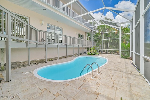 outdoor pool with glass enclosure and a patio