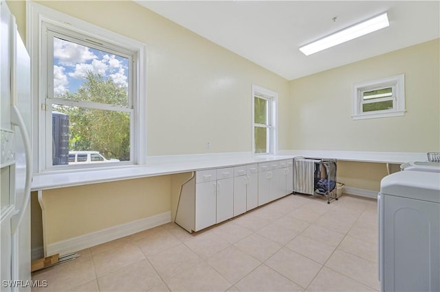 clothes washing area with cabinet space, light tile patterned floors, baseboards, and washer and dryer