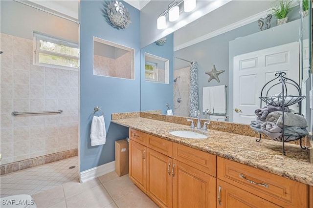 bathroom with vanity, ornamental molding, a tile shower, and tile patterned floors