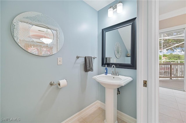 bathroom with a sink, ornamental molding, tile patterned flooring, and baseboards