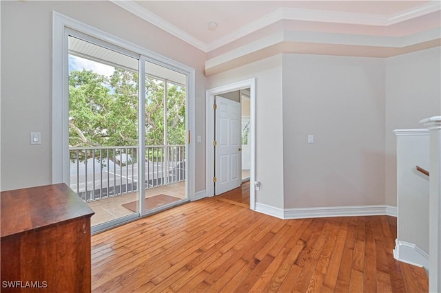 unfurnished living room featuring hardwood / wood-style flooring, baseboards, and crown molding