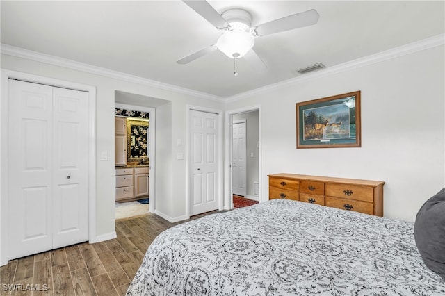 bedroom featuring ceiling fan, connected bathroom, multiple closets, and crown molding