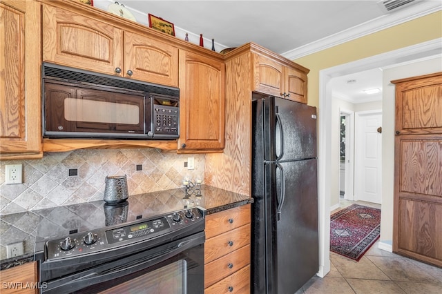 kitchen with dark stone countertops, light tile patterned floors, decorative backsplash, black appliances, and crown molding