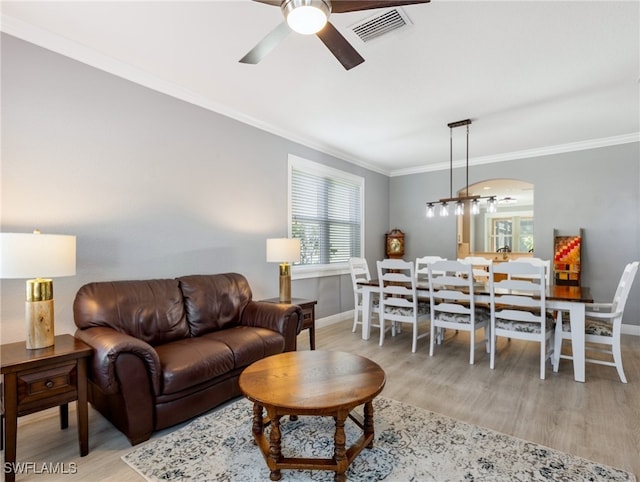 living room with crown molding, ceiling fan, and light wood-type flooring