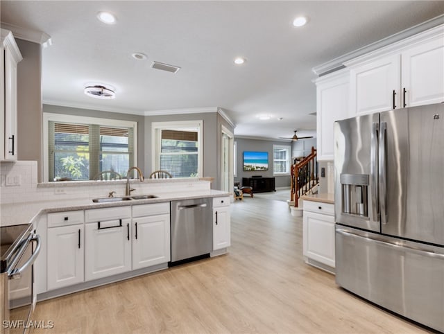 kitchen featuring appliances with stainless steel finishes, a healthy amount of sunlight, light hardwood / wood-style flooring, and sink