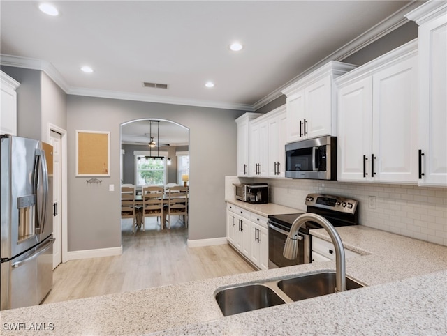 kitchen featuring light wood-type flooring, white cabinets, appliances with stainless steel finishes, and pendant lighting