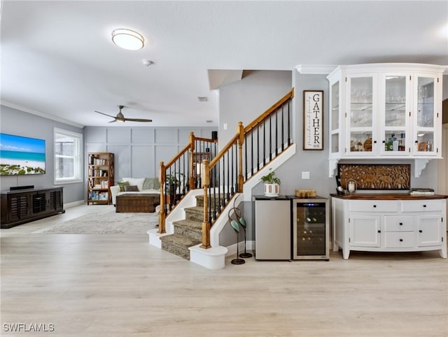 stairs featuring crown molding, hardwood / wood-style floors, wine cooler, and ceiling fan