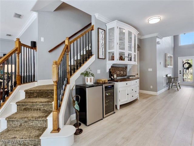 stairway featuring bar area, ornamental molding, hardwood / wood-style floors, and wine cooler