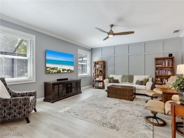 living room featuring a wealth of natural light, light hardwood / wood-style flooring, ceiling fan, and crown molding