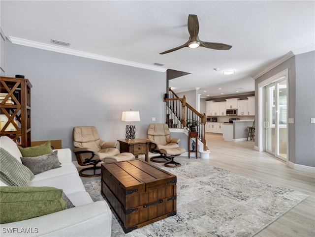 living room featuring light wood-type flooring, ceiling fan, and crown molding