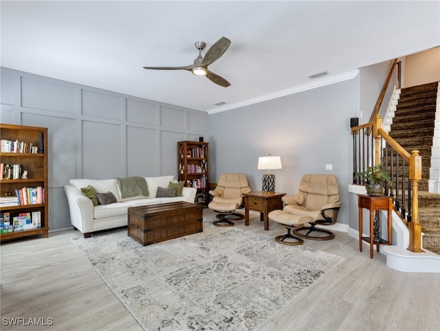 living room featuring light wood-type flooring, ceiling fan, and ornamental molding