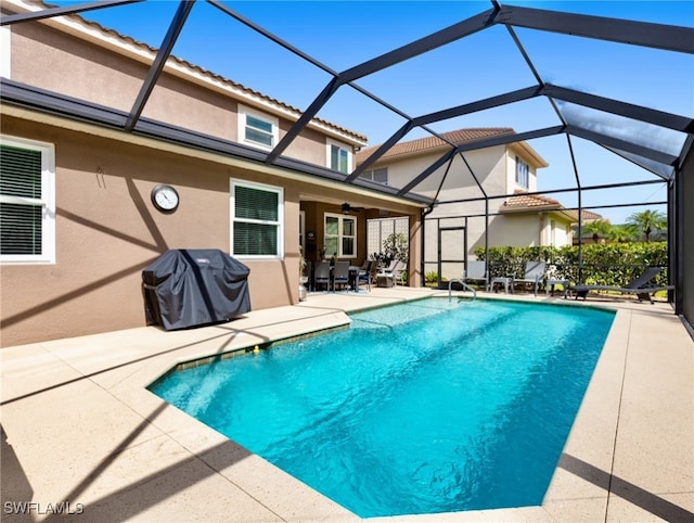 view of pool with a lanai, area for grilling, ceiling fan, and a patio