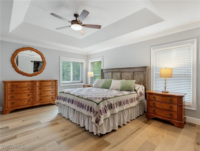 bedroom featuring light wood-type flooring, a raised ceiling, and ceiling fan