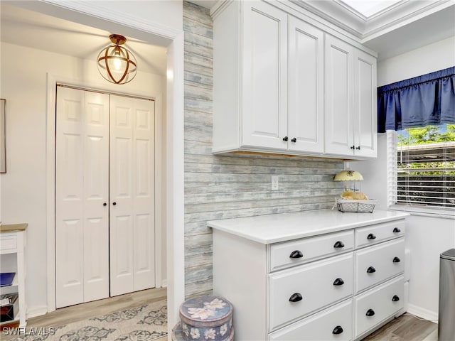 kitchen featuring ornamental molding, white cabinetry, tasteful backsplash, and light hardwood / wood-style floors