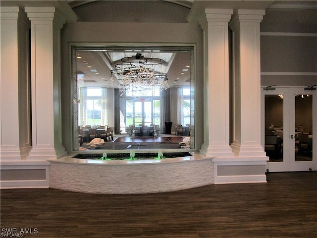 interior space with ornate columns, wood finished floors, and an inviting chandelier
