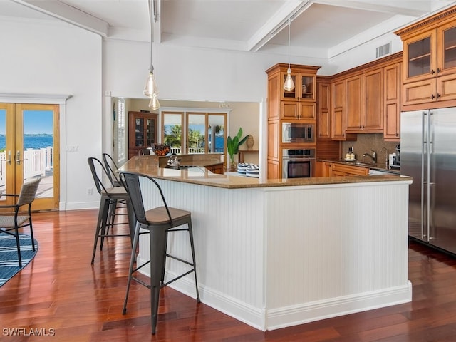 kitchen with french doors, sink, dark stone counters, dark wood-type flooring, and built in appliances