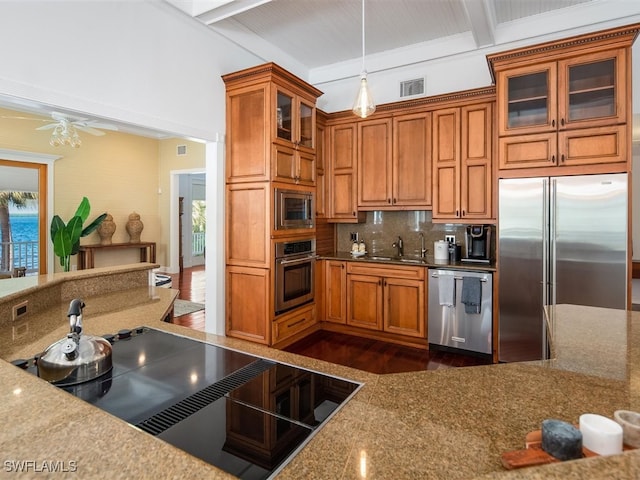 kitchen featuring built in appliances, sink, decorative light fixtures, and beam ceiling