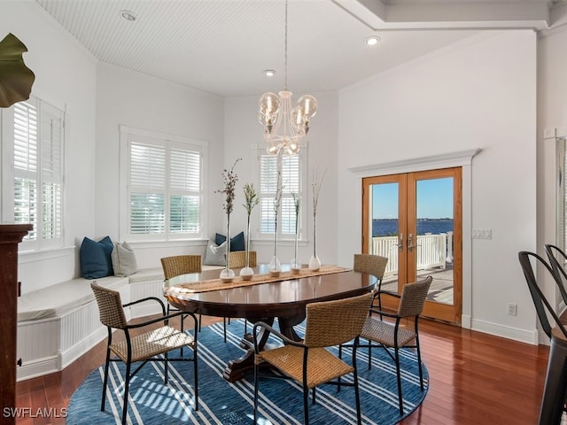 dining space featuring french doors, a water view, an inviting chandelier, and dark hardwood / wood-style floors