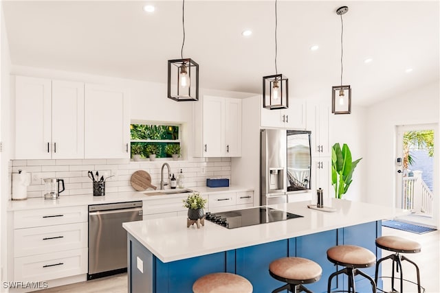 kitchen featuring stainless steel appliances, sink, pendant lighting, a kitchen bar, and a kitchen island