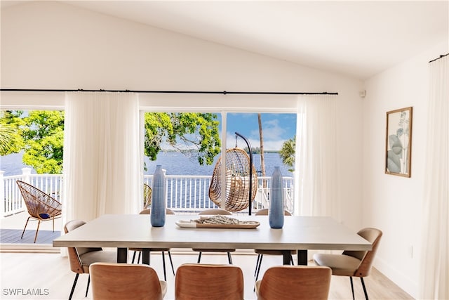 dining space with lofted ceiling, a healthy amount of sunlight, and light hardwood / wood-style flooring