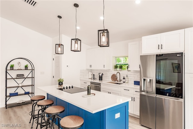 kitchen featuring a kitchen breakfast bar, a center island with sink, appliances with stainless steel finishes, sink, and white cabinetry