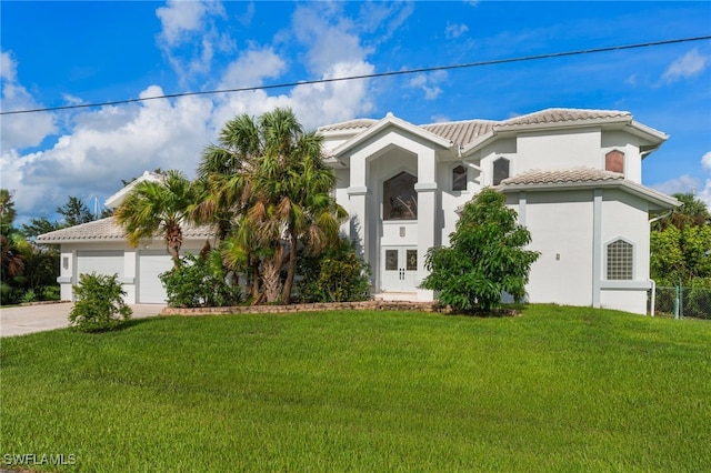 mediterranean / spanish home with stucco siding, driveway, a front lawn, and a tile roof