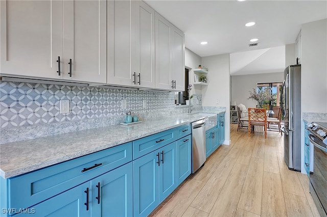 kitchen featuring light hardwood / wood-style flooring, stainless steel appliances, sink, and blue cabinetry