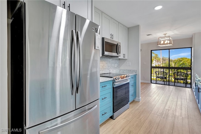 kitchen with backsplash, an inviting chandelier, light stone countertops, stainless steel appliances, and light hardwood / wood-style floors