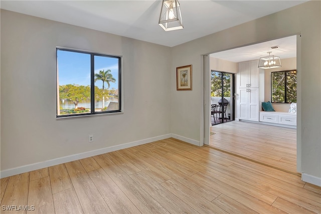 unfurnished room with a chandelier and light hardwood / wood-style floors