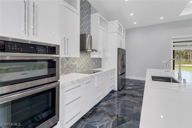 kitchen with decorative backsplash, stainless steel appliances, sink, white cabinetry, and light stone counters