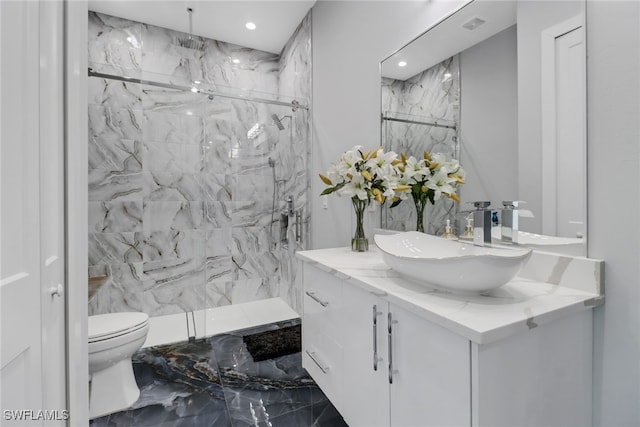 bathroom with a tile shower, toilet, and vanity