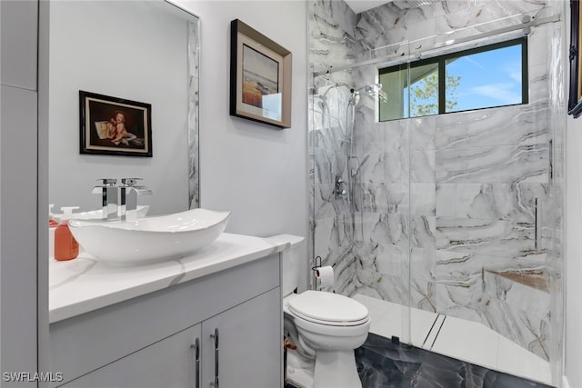 bathroom featuring vanity, toilet, and a tile shower