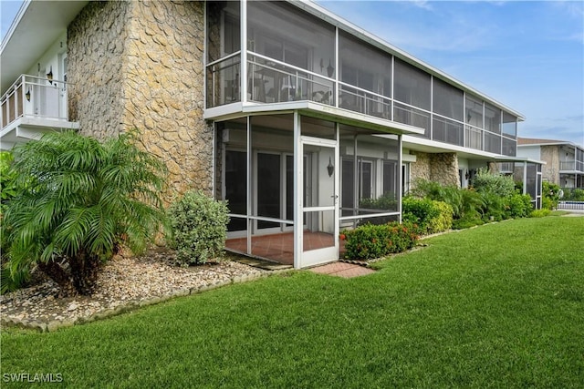 rear view of property with a sunroom and a yard