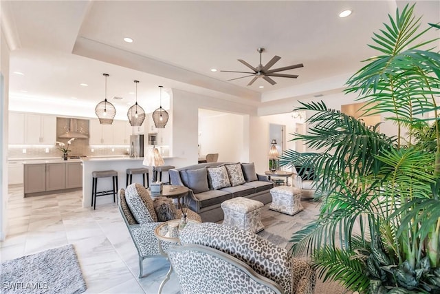 living room featuring a tray ceiling and ceiling fan