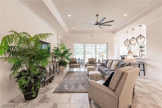 living room with ceiling fan, a raised ceiling, and ornamental molding